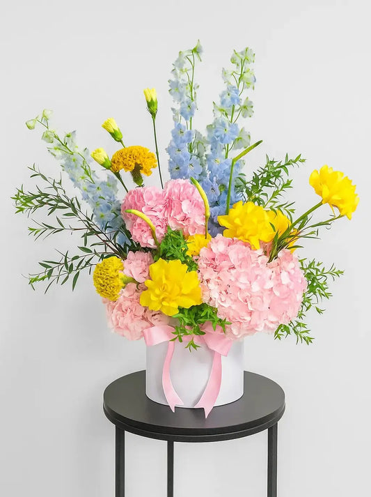 Amara Blossom luxury flower box with fresh pink and yellow flowers in a white hatbox, available for delivery in Dubai