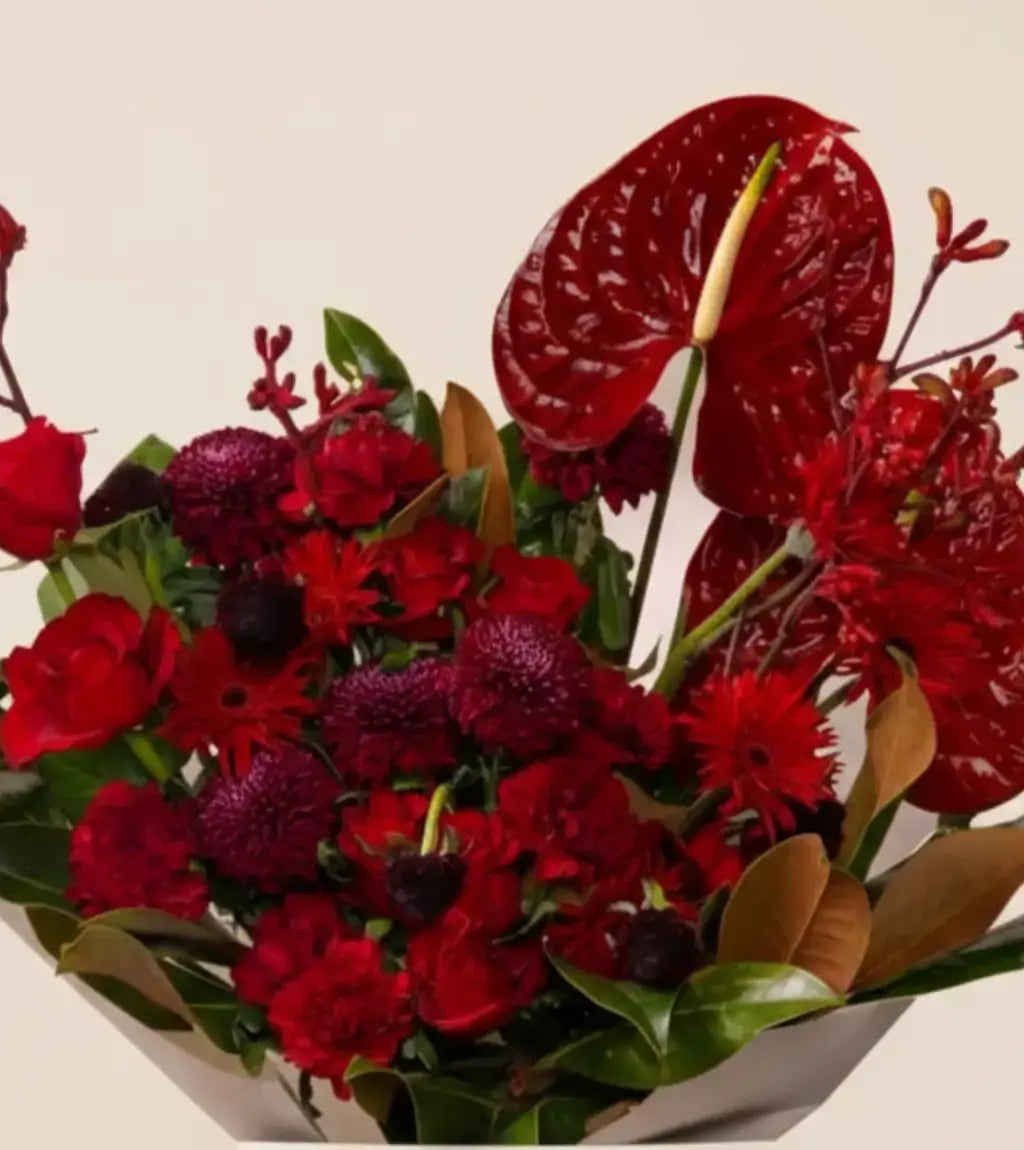 Elegant dark red flower arrangement featuring roses, scabiosa, and magnolia leaves – Berlin Bouquet same-day delivery UAE