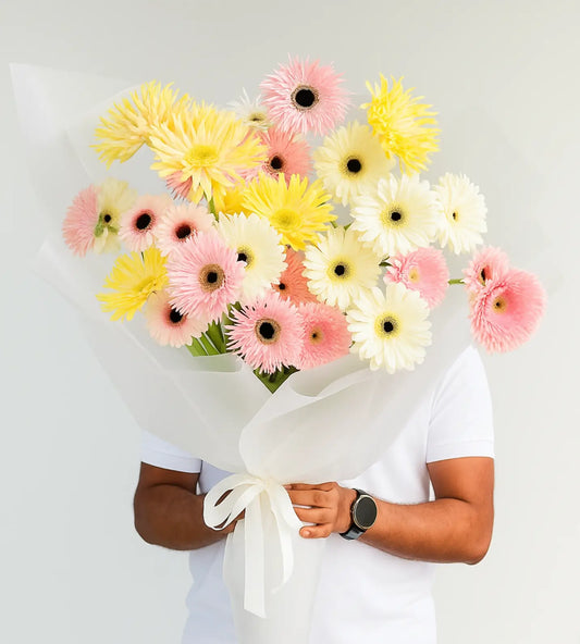 Close-up of pastel yellow, blush pink, and white gerbera flowers from the Golden Dawn Bouquet.