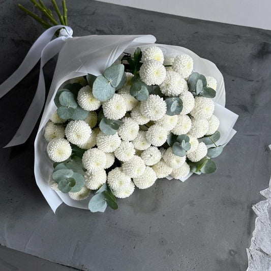 Bouquet of white flowers with green leaves on a dark surface