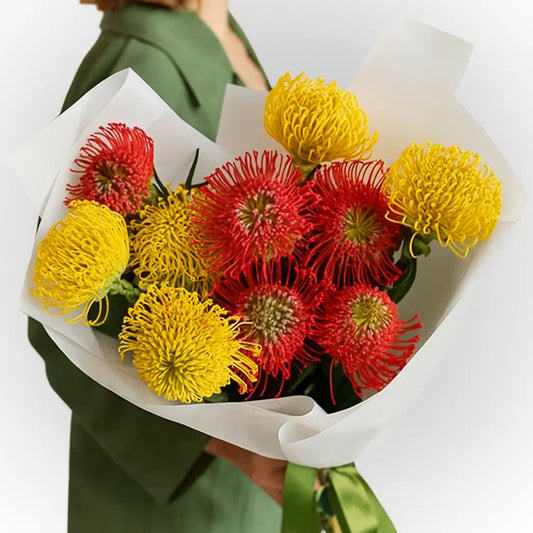 Bouquet of red and yellow flowers held by a person wearing a green jacket.