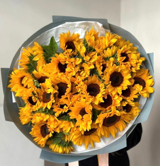 Bouquet of sunflowers in a gray wrap on a light background