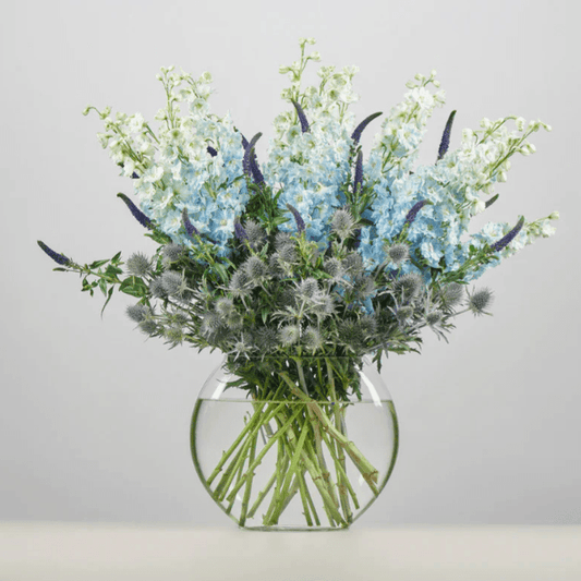 Luxury blue and silver flower arrangement in a glass vase featuring delphiniums, sea holly, and veronica. Elegant bouquet by Goshen Flower, flower delivery in Dubai.