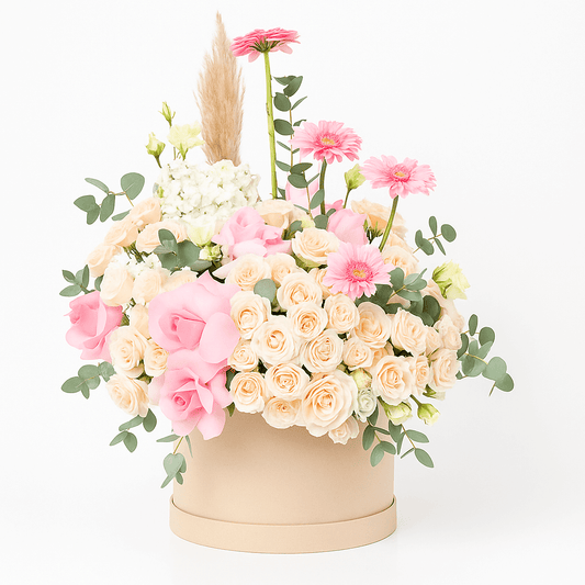 Blush pink and peach luxury flower arrangement in a beige hatbox with orchids, roses, and eucalyptus – available for delivery in Dubai